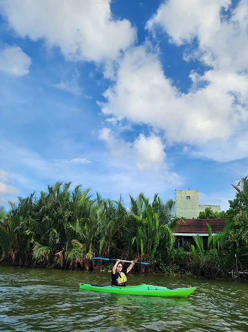 Happy kayaker lifting her row as she enters the coco palm forest