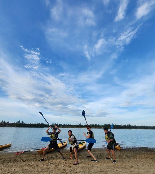 A group of friens having fun posing for a funny phot with their rows and kayaks