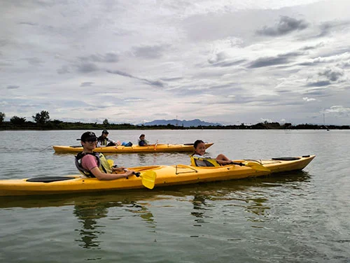 Group of friends enjoying the clowdy sky landscape as they row on the quiet river