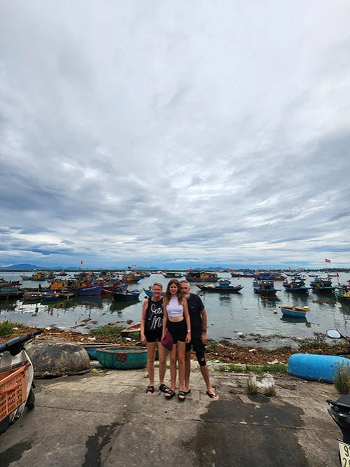 Family by the river shore in the fish market of Hoian early in the morning