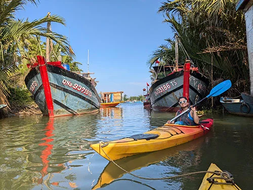 Happy traveler rowing in between two fishing boats