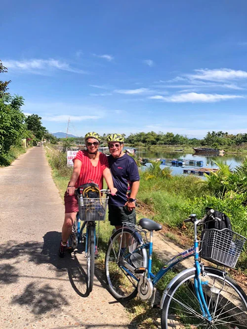 Cycle & paddle: A couple posing with their bicycles by the river.