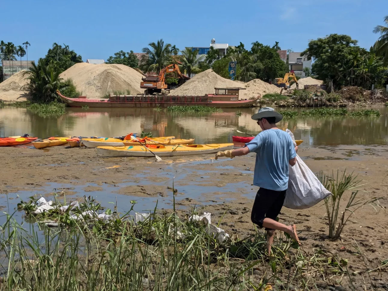 Traveler carrying a bag of rubbish by the river during a river cleanup trip