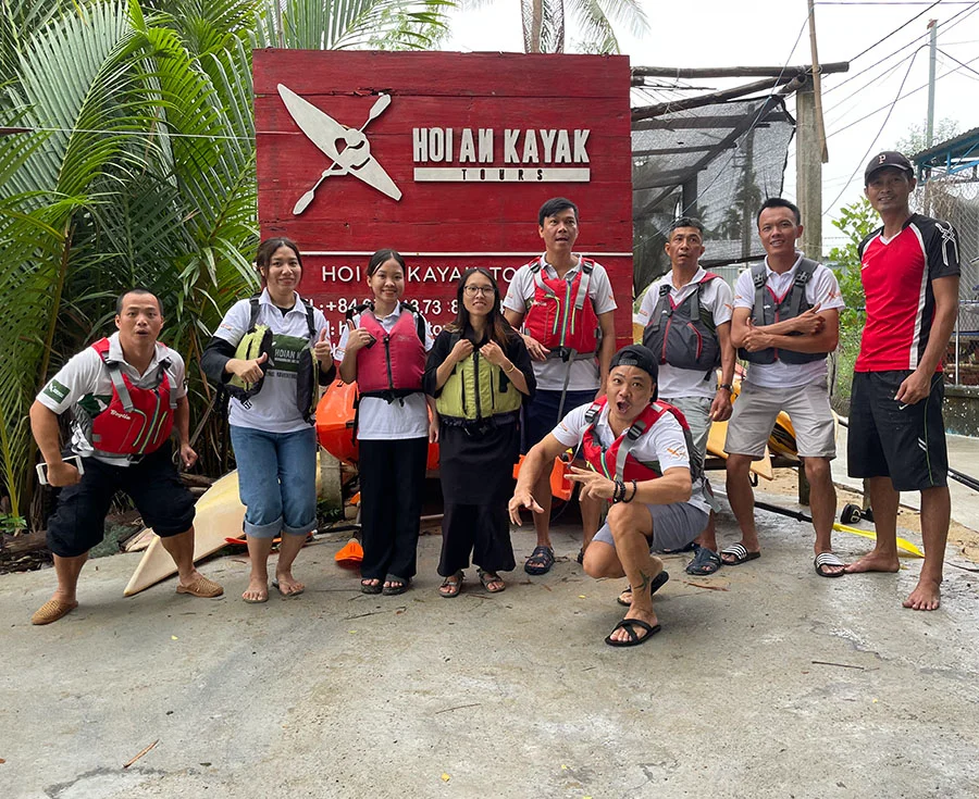 Hoian Kayak Tours team posing in front of the shop sign